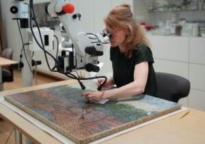 Restaurator onderzoekt een schilderij onder een microscoop
